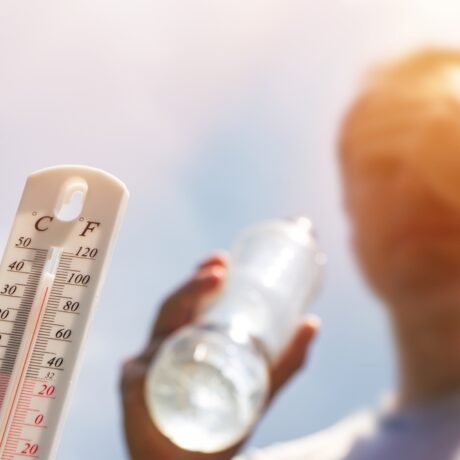 Un bărbat care ține o sticlă cu apă în mână, lângă un termometru