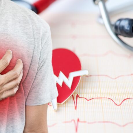 Detaliu cu bărbat care ține mâna la inimă și EKG desenat în fundal, sugestiv pentru bolile cronice cardiovasculare