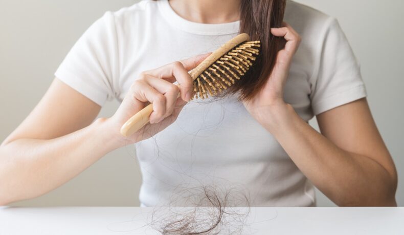 Detaliu cu femeie care își periază părul și multe fire de păr căzute