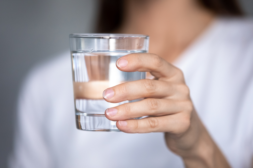 O femeie care ține un pahar cu apă în mână
