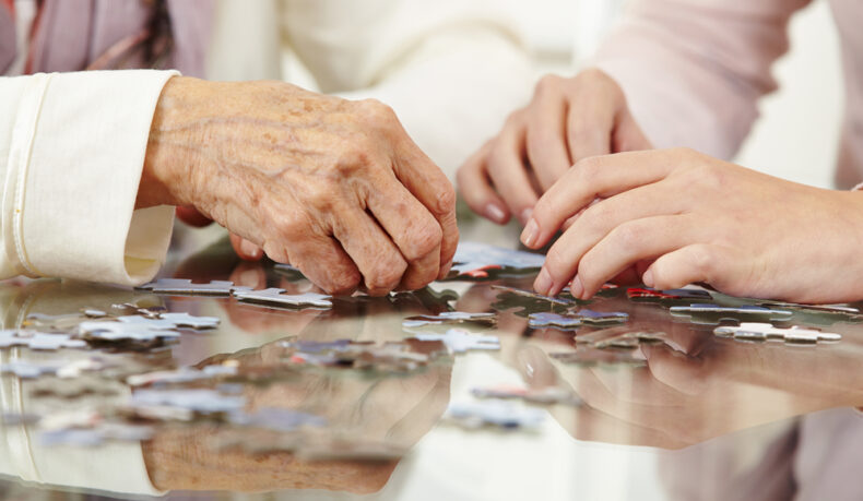 O femeie tânără și o femeie aflată la o vârstă mai înaintată rezolvă un puzzle