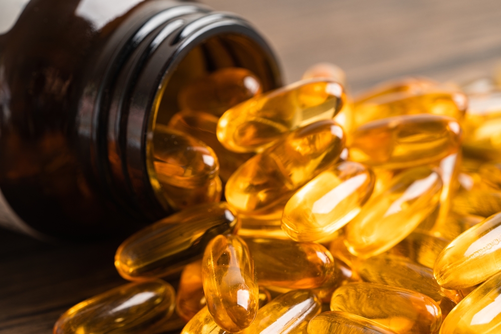 Un borcan din care se varsă capsule cu acizi grași Omega 3