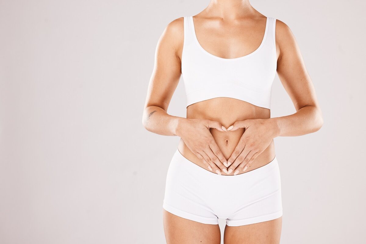 O femeie care își ține mâinile în formă de inimă pe abdomen, sugestiv pentru microbiomul intestinal și sănătatea pielii