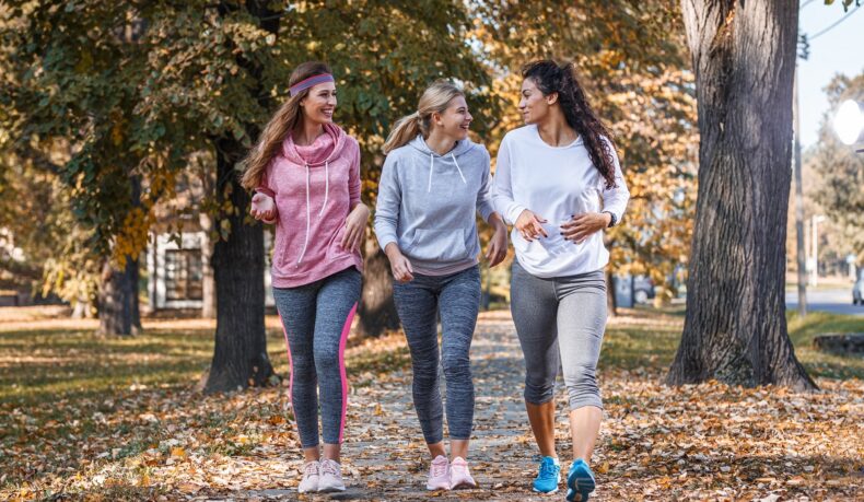 un grup de trei femei care se plimbă în parc și râd, sugestiv pentru plimbări și socializare